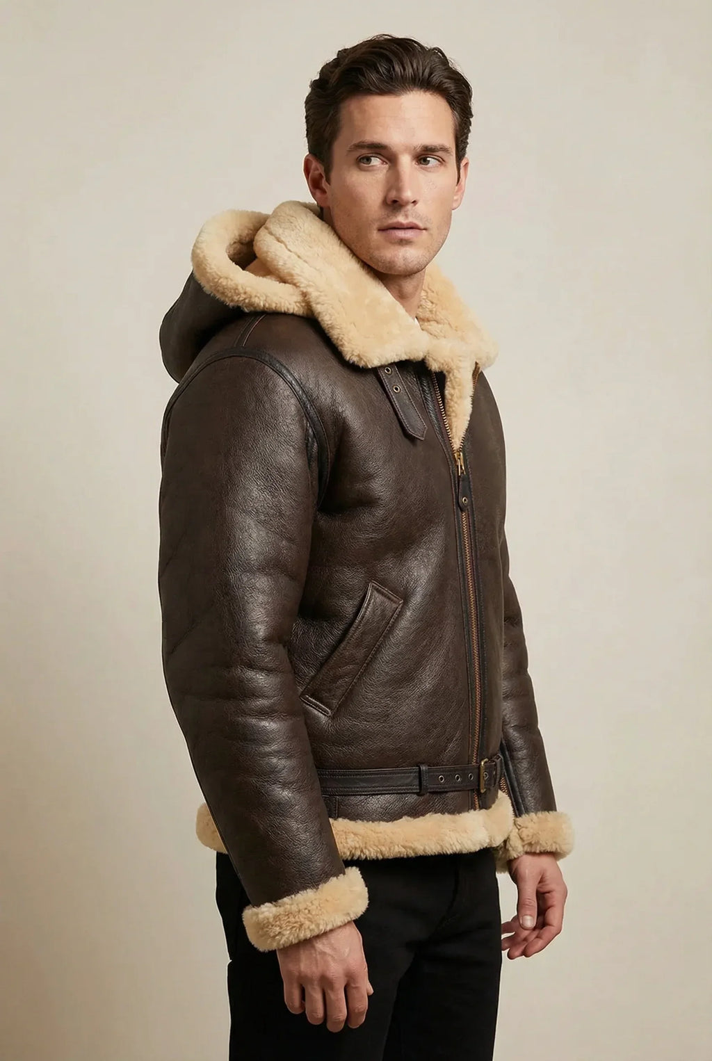 American male model wearing a brown and cream Shearlord sheepskin bomber jacket with a detachable hood in a neutral studio.
