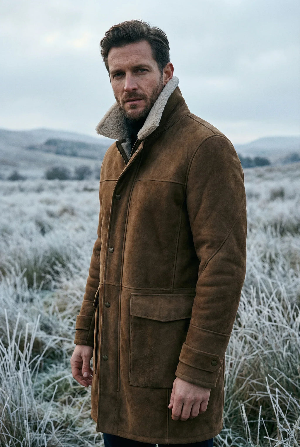 Rich American male model wearing Shearlord High Country sheepskin 3/4 long coat in whiskey brown and cream outdoors.
